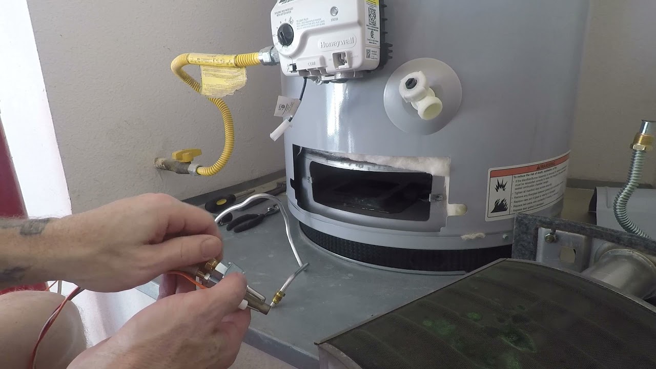 Close-up of a technician testing a gas water heater's thermocouple and gas control valve